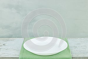 Empty plate on tablecloth on wooden table over grunge gray background