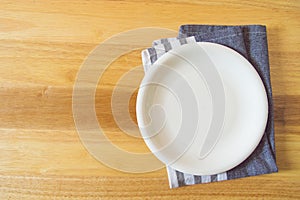 Empty plate and towel over wooden table background