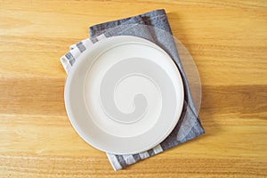 Empty plate and towel over wooden table background