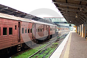 Empty platform of a railway station in Sri Lanka. Old rusty train cars. It looks like an abandoned place, but it not