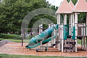 Empty playground with green slide, zip line, monkey bars and chain swings