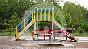 An empty playground under heavy rain, a downpour with a strong wind. big puddles, summer rainy day
