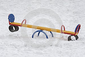 Empty playground in winter, swing tree metal multicolored flip flap. Lots of white snow cold weather no people