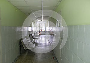 Empty polyclinic corridor with doctors` offices and patient chairs