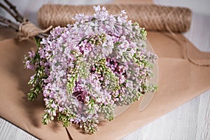 Empty postal envelope and bouquet of lilac flowers on the white wooden background, copy space. Top view.