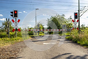 Empty railroad crossing in the countryside, on the road with open barriers.
