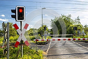 Empty railroad crossing in the countryside, on the road with open barriers.