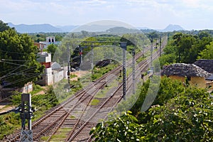 Empty railroads through lush green trees on a sunny day