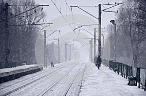 Empty railway station in heavy snowfall with thick fog. Railway rails go away in a white fog of snow. The concept of the railway