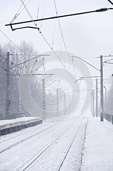 Empty railway station in heavy snowfall with thick fog. Railway rails go away in a white fog of snow. The concept of the railway