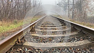 Empty railway track in gloomy weather, light fog in autumn. No train