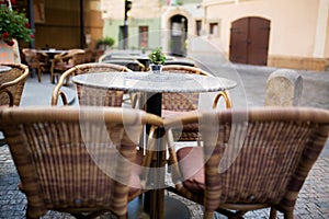 Empty rattan chairs and tables outside a street restaurant at the city