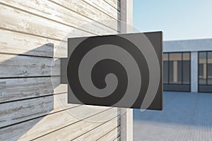 Empty rectangular black stopper on wooden building. Bright city with sunlight background. Ad, pub, cafe, or restaurant banner.