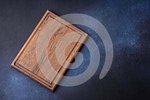 Empty rectangular wooden cutting board on dark concrete background