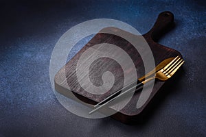 Empty rectangular wooden cutting board on dark concrete background