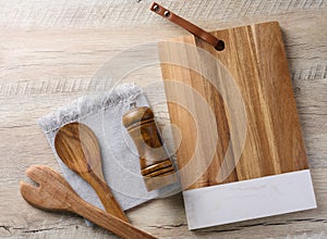 Empty rectangular wooden kitchen cutting board, empty bowl and wooden spoons on wooden table, top view