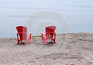 Empty red Adirondack chairs on the edge of a cliff