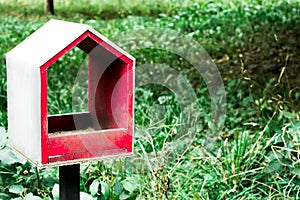 The empty red birdhouse in the green park. Save the natural environment. Sweet home