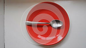 Empty Red Ceramic Plate with Silver Spoon on White Background