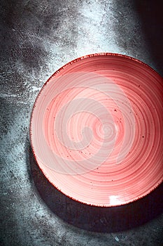 Empty red ceramic plate with spiral pattern over textured rustic concrete background