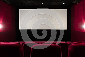 Empty red cinema hall. View of empty white cinema screen with red chairs