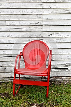 Empty red metal chair next to abandoned old building