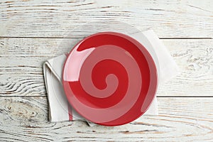 Empty red plate and napkin on white table, flat lay
