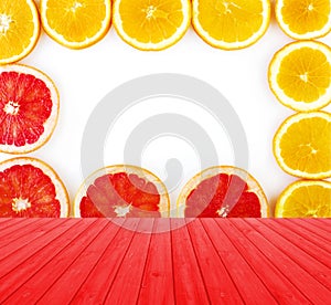 Empty red wooden deck table with fresh grapefruit and oranges rings set isolated on white background with copy space.