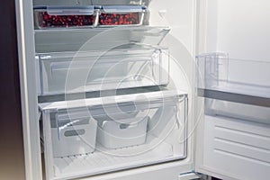Empty refrigerator shelves, view of the lower part of the compartment for storing vegetables