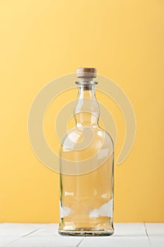 An empty relief glass bottle on a light white-yellow background