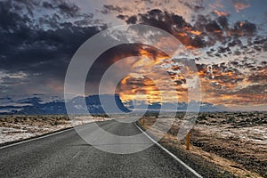 Empty road amidst volcanic landscape by mountain against dramatic sky