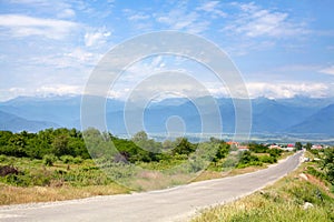 Empty road in the countryside, mountains on the horizon and blue sky with clouds background