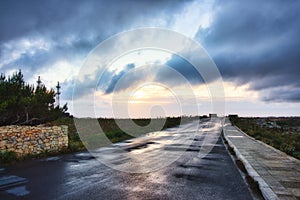 An empty road with a dramatic sky with clouds in the background