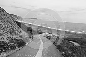 Empty road leading down on azkorri beach in black and white, basque country, spain