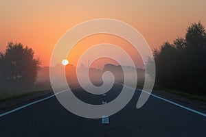 Empty Road Leading to Golden Sunrise on Foggy Morning