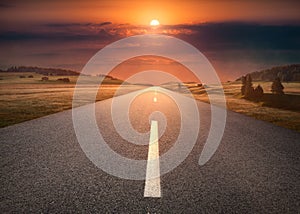 Empty road through mountain scenery at idyllic sunset