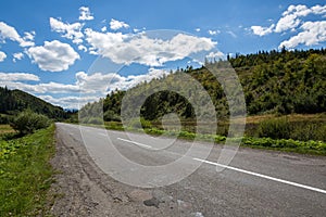 Empty road and mountains on background of the cloudy sky