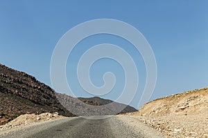 Empty road in southern Morocco with mountains in the background