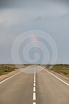 An empty road stretching to the horizon, with a rainbow in the sky, is a reminder of the endless possibilities of life