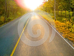 Empty road with sunlight in deep orange sky over asphalt road with slight motion blur