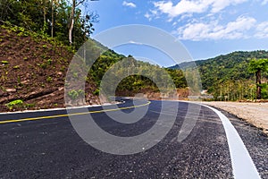 Empty road in Thailand with the mountains and blue sky as background