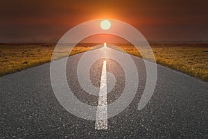 Empty road towards the sun at sunset