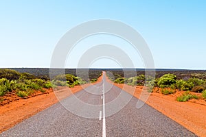 Scenic Australian outback road with red sand and bush