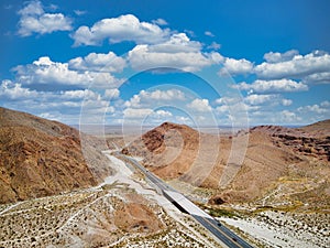 an empty road winding through the desert mountains in the middle of a desert