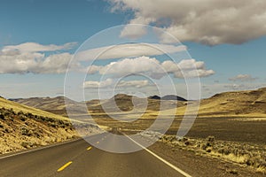 Empty Road Winding Through A Hilly Landscape 