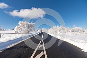 An empty road in winter leading through the mountains of RhÃ¶n