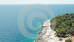 Empty rocky beach with forest and boundless tranquil sea