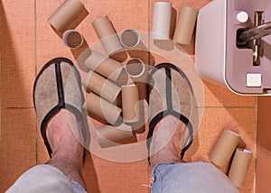 Empty rolls of toilet paper lie at the man`s feet on the toilet floor near the toilet