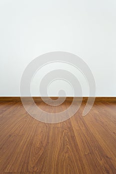 Empty room with brown wood laminate floor and white mortar wall