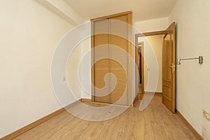 Empty room with built-in wardrobe with Venetian-style sliding oak wood doors